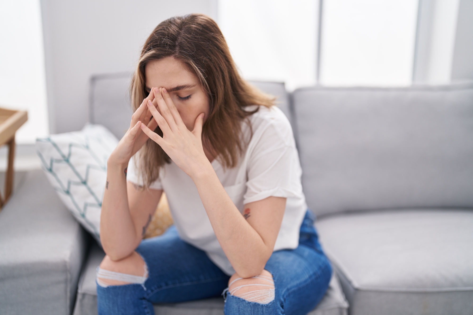 Young woman stressed sitting on sofa at home